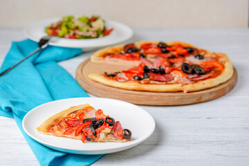 Vegetable salad with roasted meat and cheese and Sliced whole salami pepperoni pizza on a wooden table.