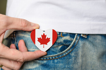Patriot of Canada! Wooden badge with the flag of Canada in the shape of a heart in a man's hand.