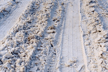 Road covered with snow, winter driving, dangerous road conditions. Tire tracks on snowy road, ice under the snow. Traction on winter road. Selective focus