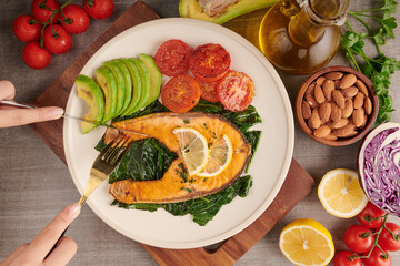 Grilled salmon fish fillet and fresh green lettuce vegetable tomato salad with avocado guacamole. Balanced nutrition concept for clean eating flexitarian mediterranean diet.