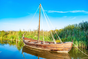 Old wooden boat on lake. Wood empty rowboat moored near shore