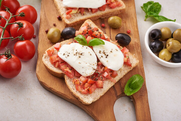Bruschetta with tomatoes, mozzarella cheese and basil on a cutting board. Traditional italian appetizer or snack, antipasto. Caprese salad bruschetta. Top view with copy space. Flat lay.
