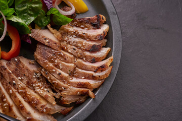 Grilled steak with fresh vegetable, sweet pepper, tomatoes, red onion, pink pepper and spices. Home made tasty food. Concept for tasty and healthy meal. Black stone background. Pork steak with salad
