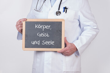 Arzt mit einer Tafel auf der Körper, Geist und Seele steht