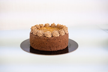  Delicious chocolate and caramel cake on black plate, white background.