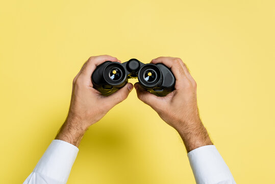 Cropped View Of Man Holding Black Binoculars In Hands On Yellow