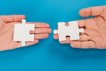 top view of female and male hands with jigsaw on blue
