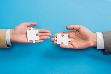 top view of male and female hands with jigsaw on blue