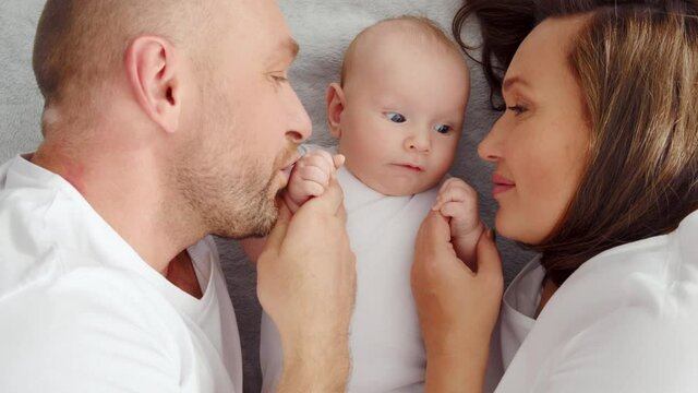 Happy family. Newborn baby with happy parents, top view. Healthy newborn baby in a white t-shirt with mom and dad. Close up Faces of the mother, father and infant baby.  Cute  Infant boy and parents