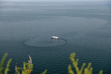 The yacht is turning around on Lake Baikal near the Cape Khoboy. Olkhon Island, Russia.