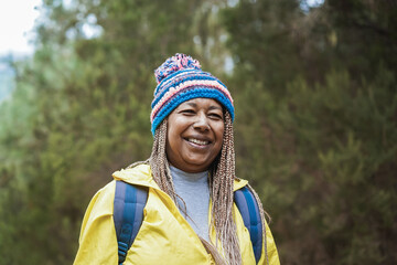 Happy african senior woman having fun during trekking day in to the wood - Focus on face