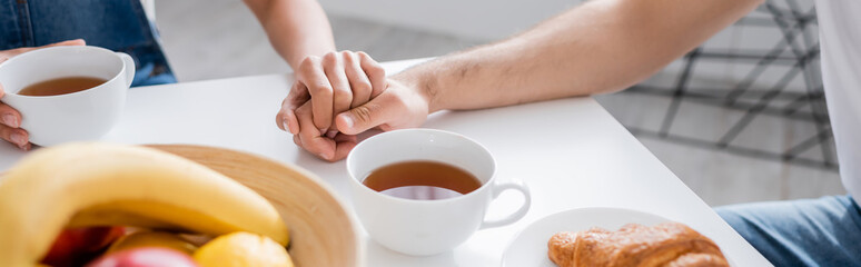 cropped view of couple holding hands during breakfast, banner