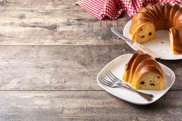 Traditional bundt cake piece with raisins on wooden table.Copy space