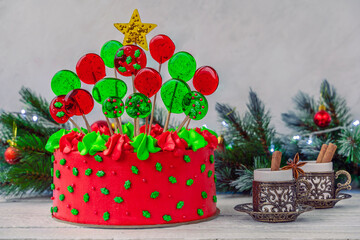 Christmas cake with balls in the shape of christmas tree, garland, coffee cups. Decoration for the holiday. Beautifully served table for the celebration.