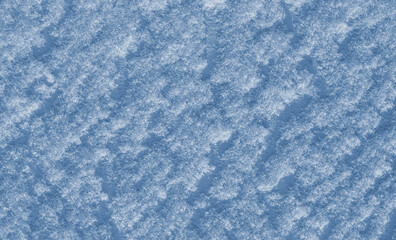 The texture of fresh natural snow on the surface of a blue cement wall.Background for holiday greeting cards Christmas, New year