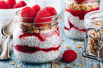 Chia Pudding. Healthy vanilla raspberry chia pudding in a glass jar with fresh berries and granola...