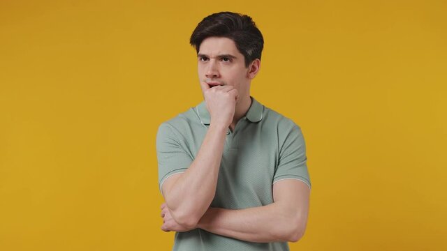 Excited insighted smart proactive pensive young man 20s years old wear blue t-shirt looks around thinks scratches at temple comes up with ideas raised finger isolated on plain yellow background studio