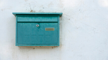 Buzón metálico verde en pared blanca