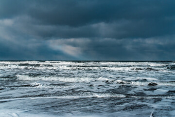 Winter landscape with frozen sea and icy beach. Storm and snow weather. Dramatic seascape.