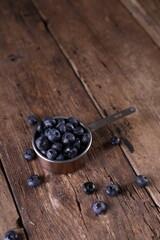 Blueberries in a small measuring glass on a wooden background