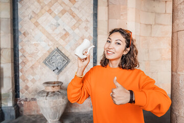 Happy Asian woman drinks natural thermal water from a mineral spring and showing thumb up sign....