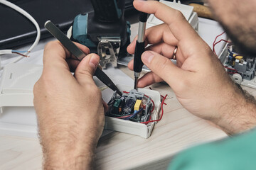 Repair of electronic devices, tin soldering parts. Hands of man holding screwdriver. Computer circuit board