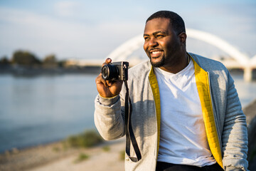 Modern black man enjoys  photographing  cityscape.