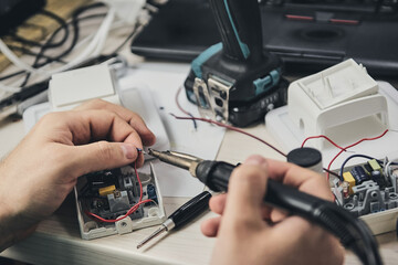 Repair of electronic devices, tin soldering parts. Hands of man holding screwdriver. Computer...