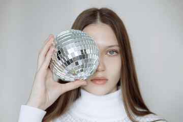 Fashion portrait of a teenage girl with a disco ball, covering her face