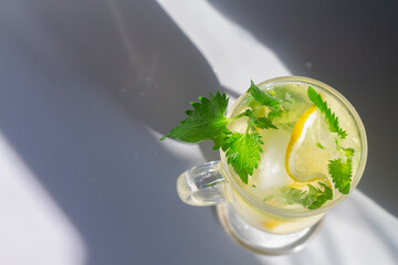 Lemon mojito drink with mint leaves in glasses on a gray background with clear shadows