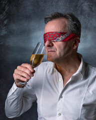 A blindfolded man sniffs a glass of wine to smell its aroma