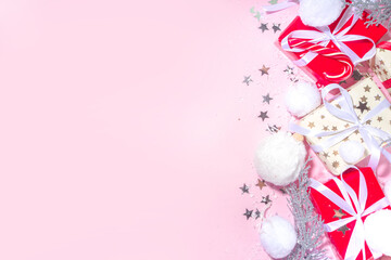Fluffy Christmas concept. Festive Christmas background with fluffy decoration stuff, xmas ball, gift boxes, with artificial snow and shiny stars on pink color background copy space
