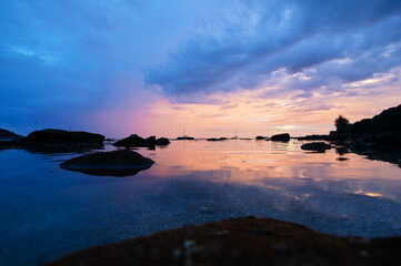 Beautiful landscape with colorful sunset on the sea rock beach.
