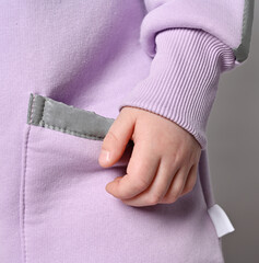 Closeup of kid girl in pink jumpsuit with pockets with retroreflective safety stripes over grey background. Pockets, cuffs