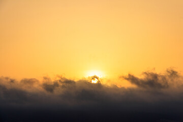 Fototapeta premium Beautiful rising orange sun above the clouds in sky at sunrise