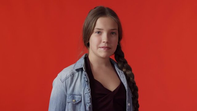 A young teenage Caucasian girl with a long braid smiles as she looks into the camera
