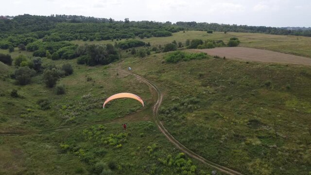 a man with a parachute in a hilly landscape
