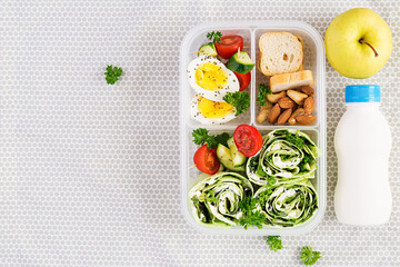 School lunchbox. Healthy lunch box with tortilla wraps with cream cheese, cucumber and letucce. Nuts,apple and vegetable. Top view, flat lay