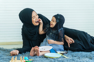 Joyful little lovely toddler girl muslim with own motherhood sitting togetherness on the floor...