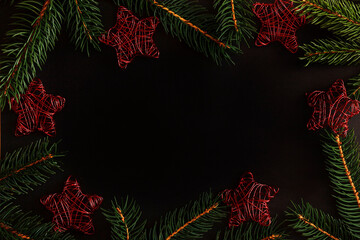 Christmas background new year dark frame with fresh christmas tree branches and red new year toys stars. Gift card closeup with spase for text