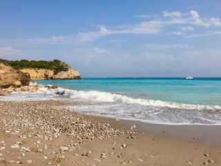 Obraz premium Rocky sandy beach, coastline with turquoise sea, wave splash, Catalonia, Spain