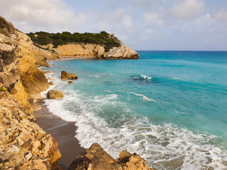 Rocky sandy beach, coastline with turquoise sea, wave splash, Catalonia, Spain