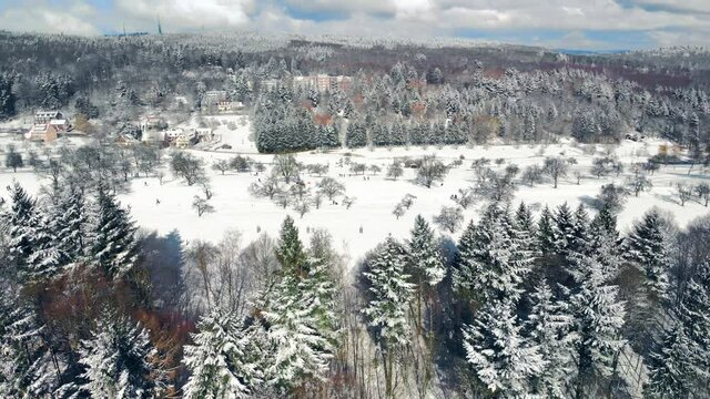 Scenic winter landscape aerial footage with snow covered meadows surrounded by conifer forests and hills