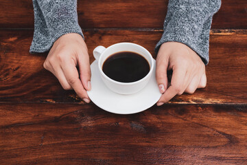 Fototapeta na wymiar woman's hand holding a coffee cup on a wooden table