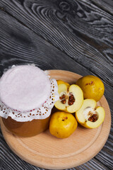 Quince fruits on a cutting board. Quince jam. The yellow fruit is cut, the seeds are visible. Plate on black pine boards. Close-up shot.