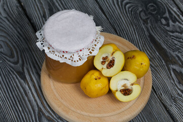 Quince fruits on a cutting board. Quince jam. The yellow fruit is cut, the seeds are visible. Plate on black pine boards. Close-up shot.