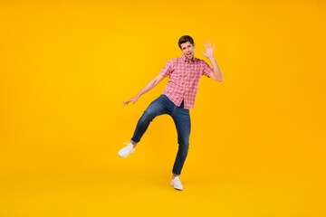 Fototapeta na wymiar Full body photo of young man happy positive smile enjoy music dancer wave hand hello isolated over yellow color background