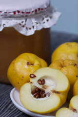 Quince fruits on a plate. Quince jam. The yellow fruit is cut, the seeds are visible. Plate on black pine boards. Close-up shot.