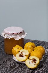 Quince fruits on a plate. Quince jam. The yellow fruit is cut, the seeds are visible. Plate on black pine boards. Close-up shot.