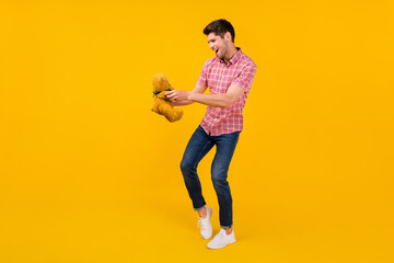 Full length body size view of attractive cheerful funky guy dancing with bear toy isolated over bright yellow color background